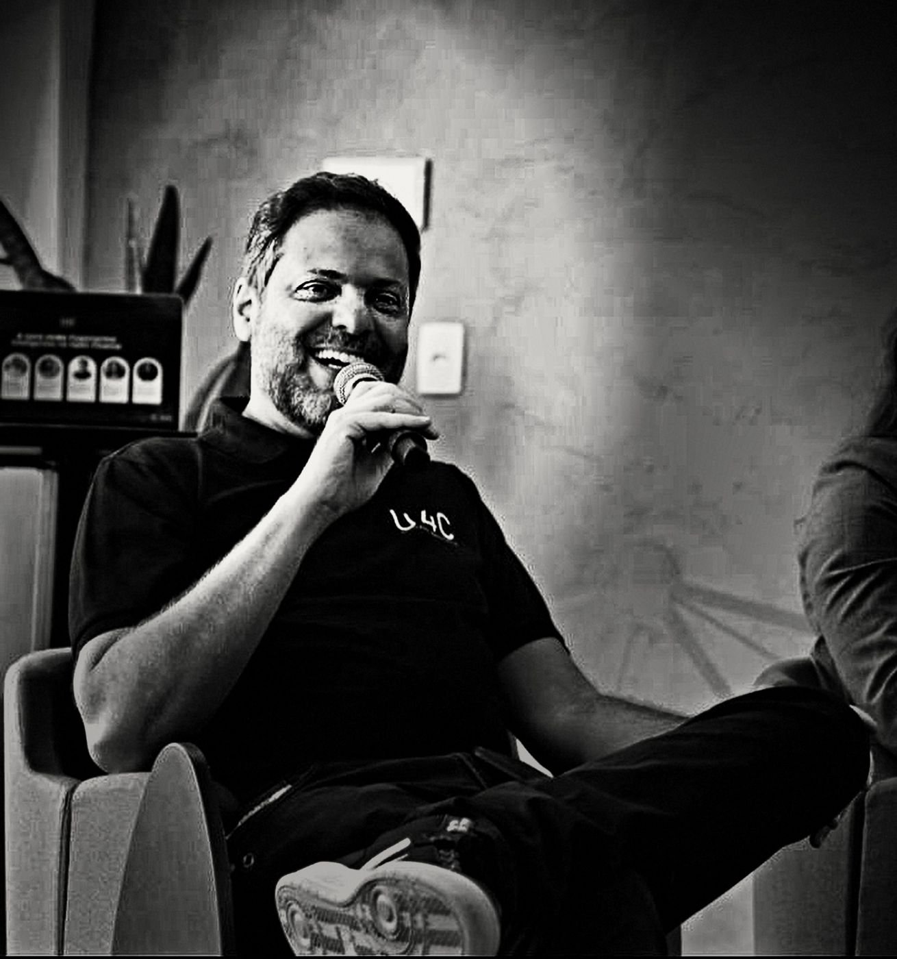 Túlio Iannini ao microfone, sorrindo, durante um painel